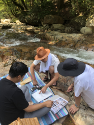 松野町、滑床渓谷での青空MTGの様子。各プロジェクトは、サン・クレア社員だけではなく、プロジェクトへ強い共感をいただいた、各プロフェッショナルが集まって進んでいきます。参画している方は、会社名ではなく、個人の名前で商売／勝負をしている方ばかり。