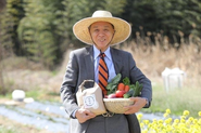 弊社で育てた米・野菜を持つ代表の遠藤