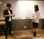 今月から愛媛県でリモートワークに切り替わるメンバーのフロア壮行会にて、社長より会社初となる＜人事発令書＞を読み上げる一幕。彼女一人だけではなく、会社としての新たなチャレンジです。