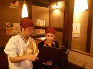 串むすびにてアルバイトを指導をする店長