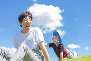 青空の下で社員の子供と遊ぶ代表の小西。束の間の息抜きも大事にしています。