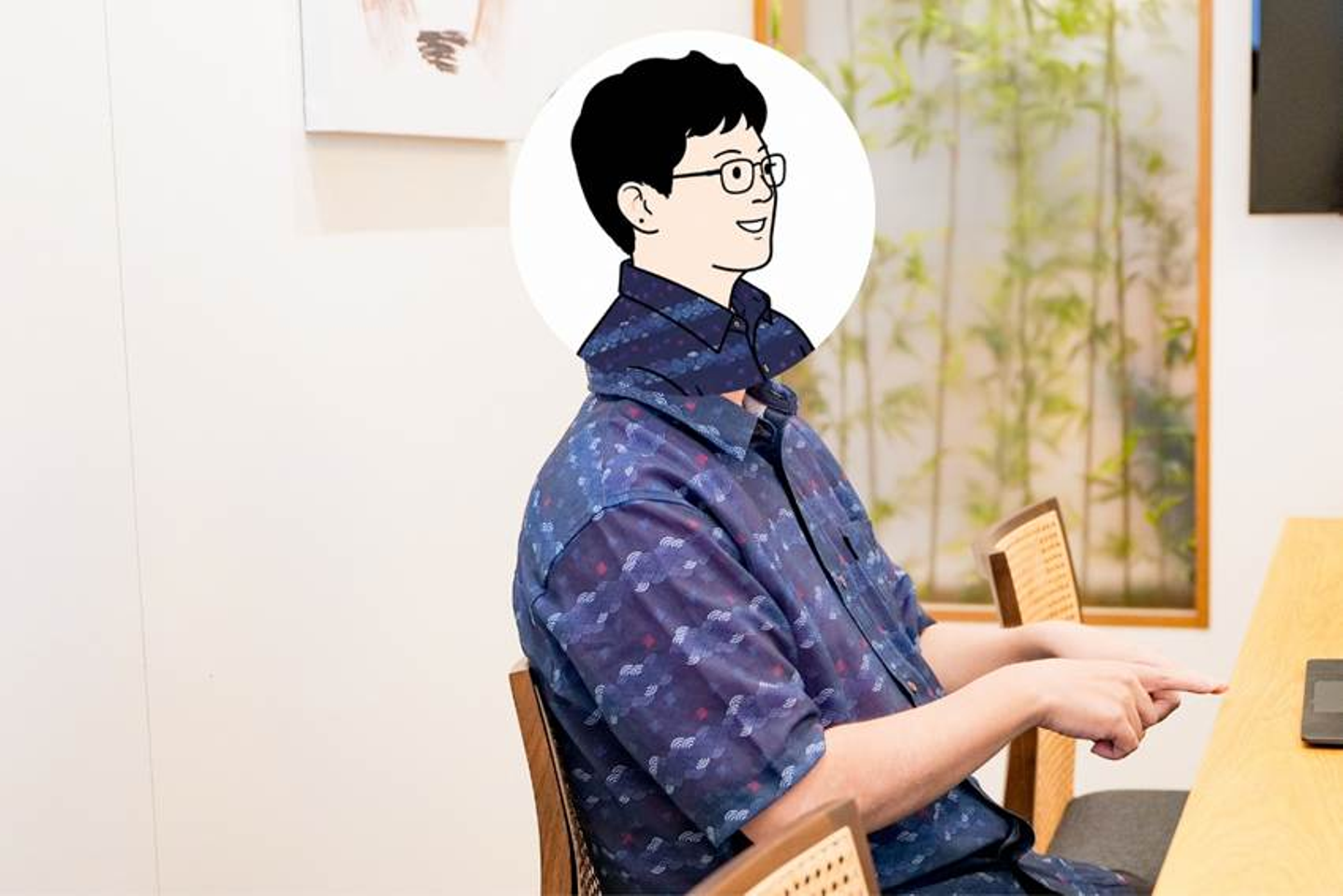 The image depicts a person sitting at a desk, wearing a dark blue shirt with a pattern, holding a tablet, and there's a small plant in the background.

AI 生成コンテンツは誤りを含む可能性があります。
