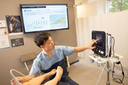 私たちは、一つの検査だけで診断することはありません。歩行動画で動きを確認し、レントゲンで骨やアライメントを評価し、エコーで筋肉・腱・靱帯・関節の状態をリアルタイムに確認します。それぞれの検査には役割があり、得られた情報を組み合わせることで、一人ひとりの症状の原因を多角的に評価しています。また、検査や診療は職種ごとの専門性を活かした分業制を採用しています。診断やエコーなど医師にしかできない業務は医師が責任を持って行い、歩行動画の撮影や各種測定、患者さんへの説明などは看護師や理学療法士をはじめとしたスタッ